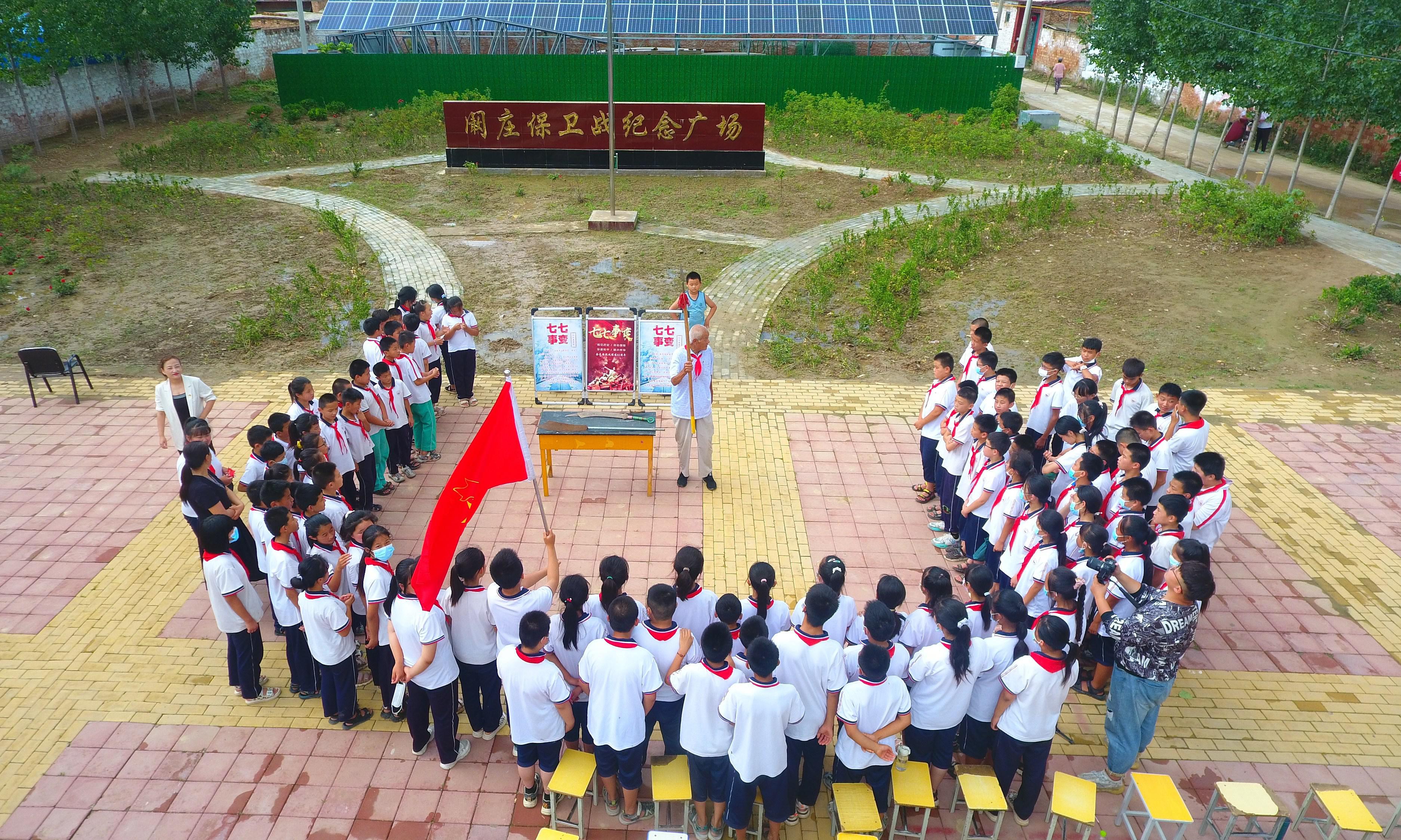2022年7月6日,山东省聊城市,在茌平区菜屯镇阚庄村的阚庄保卫战纪念广场,阚庄保卫战亲历者王光木老人,为小学生们讲述抗战故事,展示大刀、长矛。